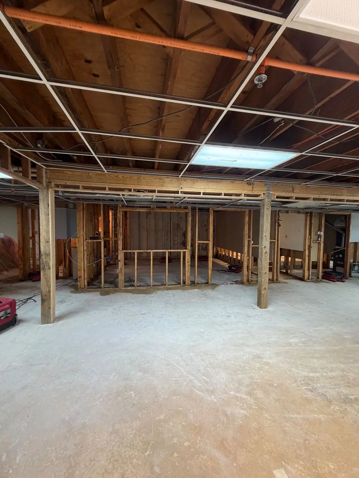 A basement after water damage, with dryers running and partition walls stripped to the studs