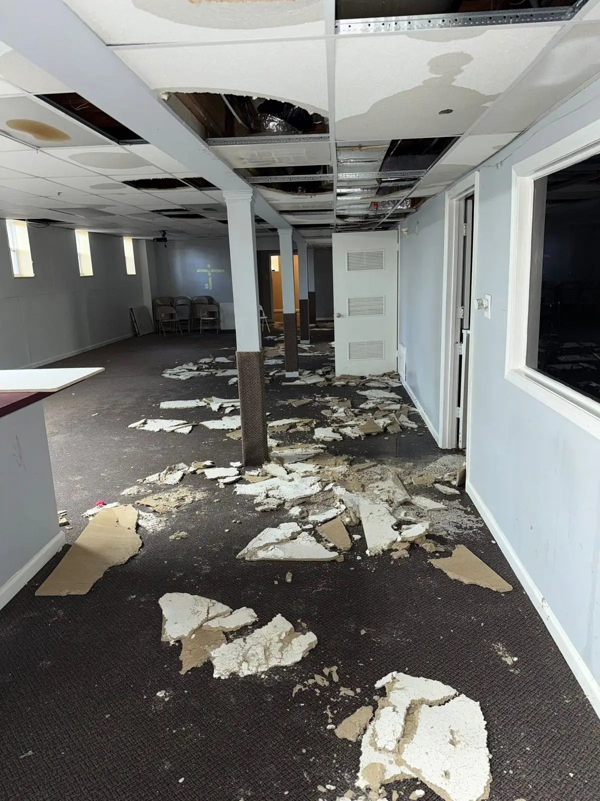 Ceiling tiles fallen onto the carpet of a large room after water damage