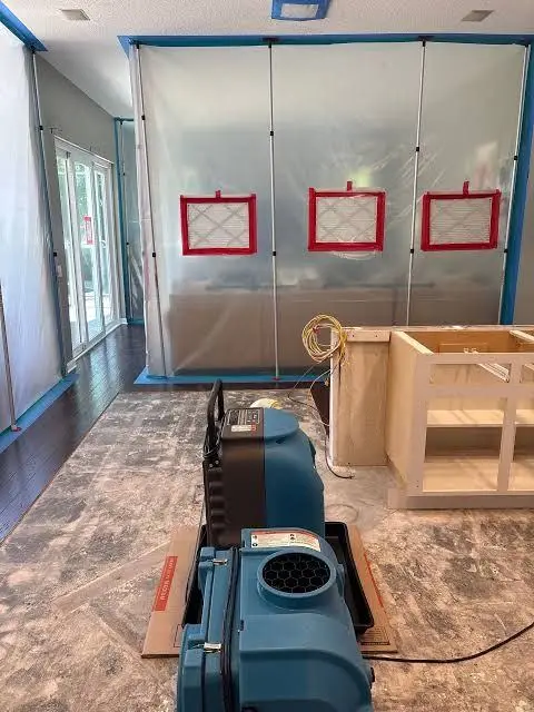 Plastic containment barrier with red tape and an air mover in the foreground