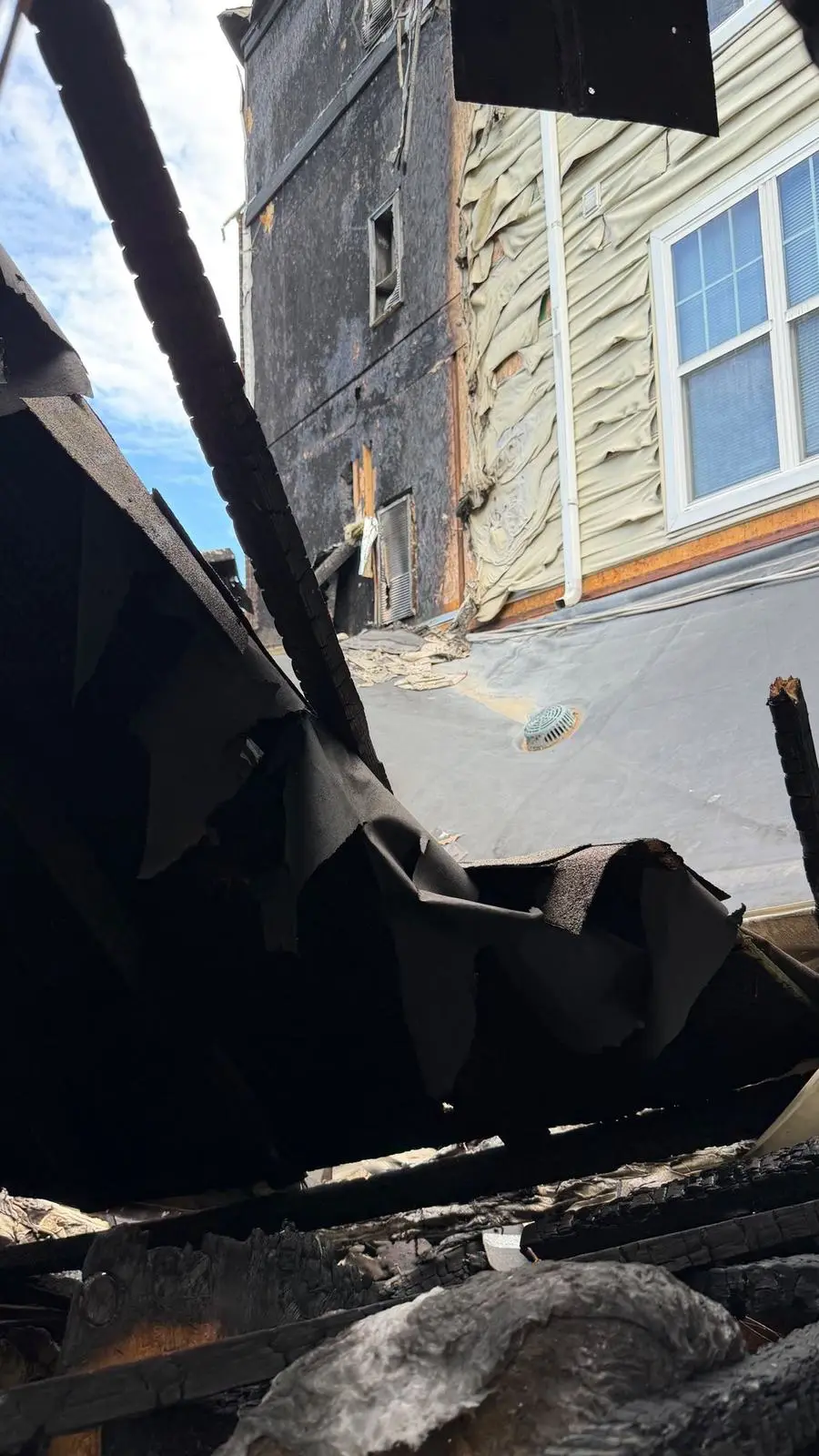 Fire-damaged building with charred walls and melted siding