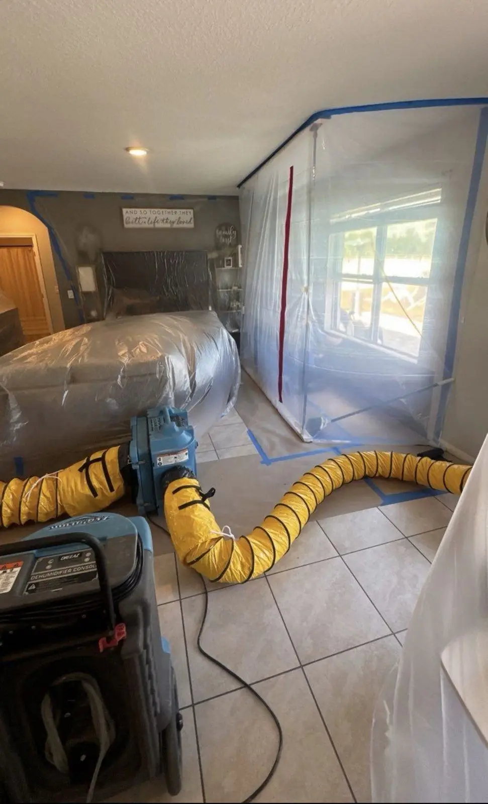 Negative air containment with a yellow duct and an air scrubber inside a home