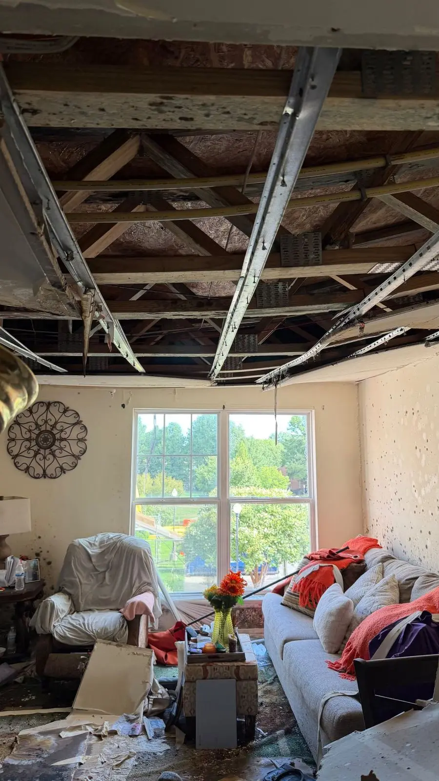 Opened ceiling with stained joists and spotted walls in a living room after water and fire damage